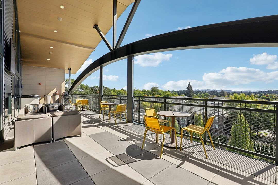 A balcony with a table and chairs overlooking a cityscape.